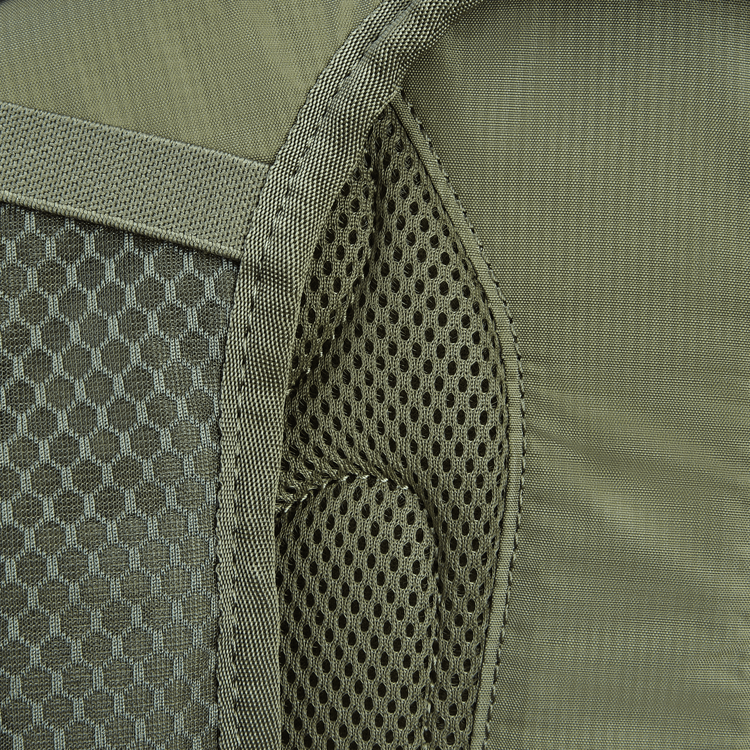 Close-up of the Vertx Long Walks Pack 28L, featuring a green backpack with a left mesh pocket and textured gray stripe. The fabric has honeycomb on one side and smooth on the other, perfect for adding body armor inserts for extra safety.