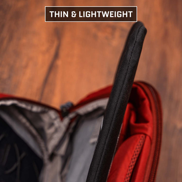 A Premier Body Armor 9 x 13.5 Insert Level IIIA Armor (Multicam Black) is being placed in a red backpack’s open compartment, with "THIN & LIGHTWEIGHT" shown at the top—providing discreet ballistic protection.