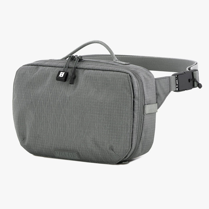 The Viktos Upscale Hip Pack by Viktos/Premier is a gray crossbody bag featuring a rectangular shape and woven texture. It includes a zippered main compartment, small front pocket with snap closure, adjustable strap with buckle, and a top handle for easy carrying.