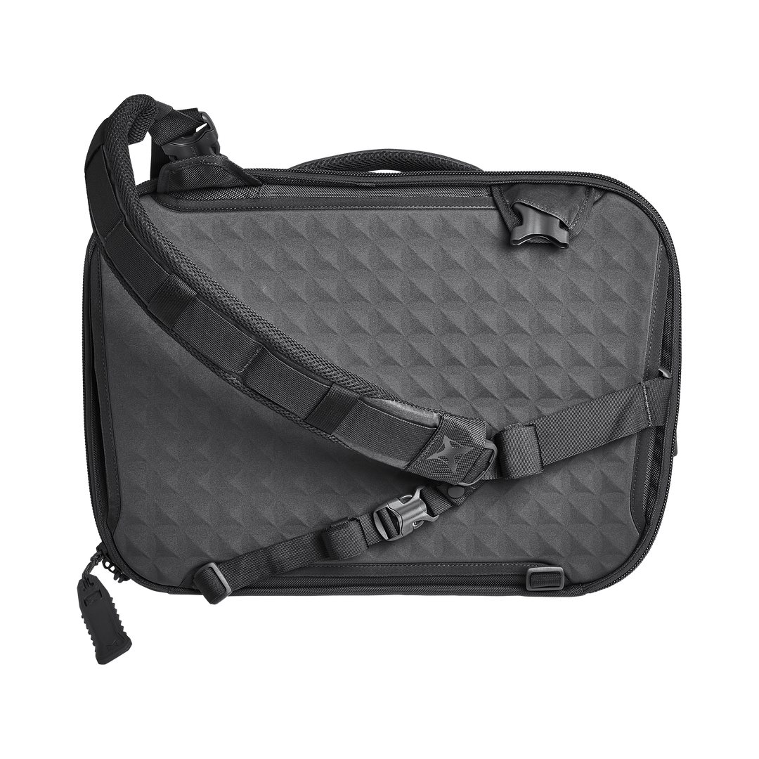 The Vertx Keryx Sling from Vertx features a textured diamond pattern, multiple adjustable straps with buckles, a top handle, and a padded shoulder strap for comfort, offering modern style and function similar to an Armored Vertx.
