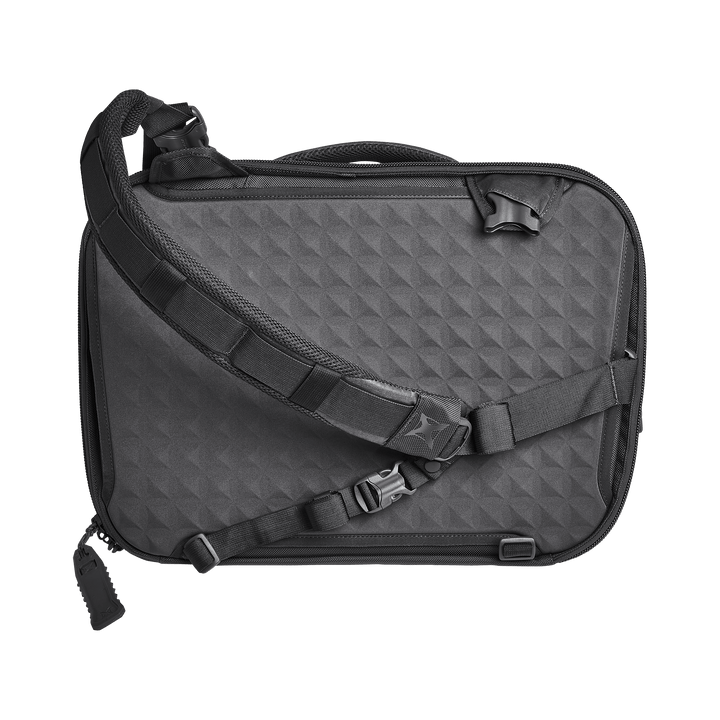 The Vertx Keryx Sling from Vertx features a textured diamond pattern, multiple adjustable straps with buckles, a top handle, and a padded shoulder strap for comfort, offering modern style and function similar to an Armored Vertx.