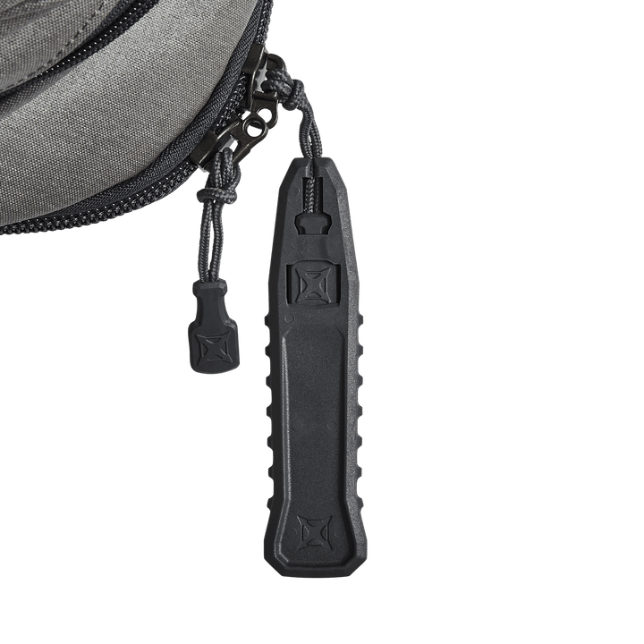 Close-up of a gray fabric zipper on the Vertx Commuter 3.0 Sling, featuring the Rapid Access Pull design with a textured black zipper pull. The braided cord and stitching detail enhance its tactical functionality for body armor insert compatibility.