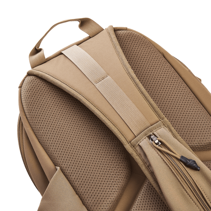 Close-up of a tan Vertx Siege 15L Tactical Sling featuring padded shoulder straps. The mesh-like fabric boosts breathability, and a side zipper pocket adds tactical functionality, combining comfort and practicality for any adventure.