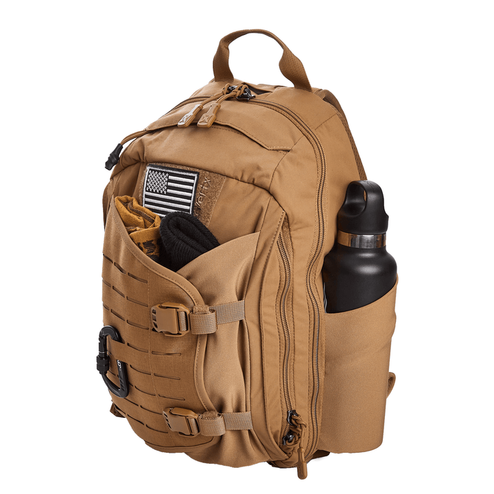 The Vertx Siege 15L Tactical Sling, in Coyote color, is designed for ultimate tactical readiness with multiple compartments and straps. It features an American flag patch, a CCW compartment, and a side pocket securing a black water bottle. The handle is visible at the top.