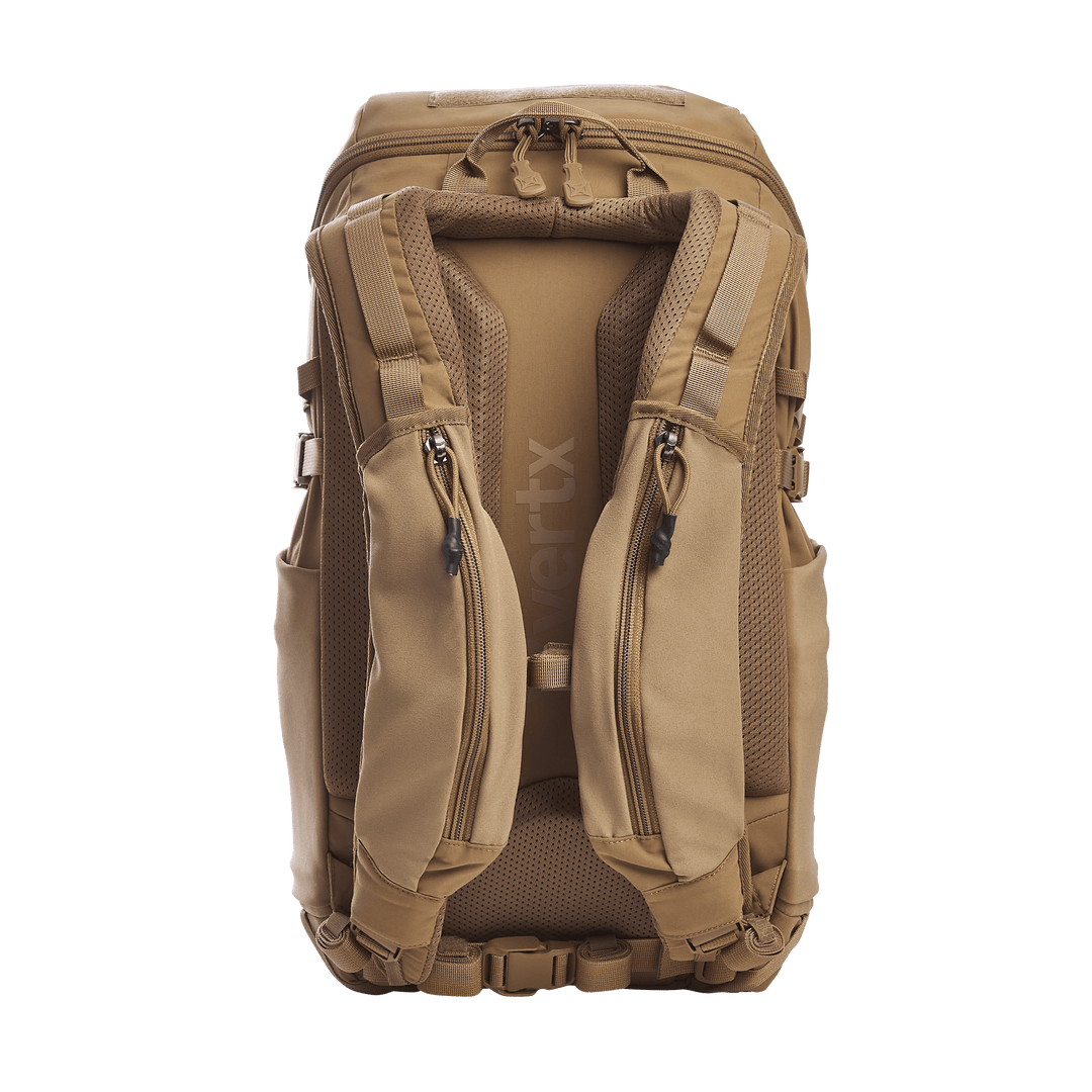 The Vertx Siege 25L Tactical Pack, in brown, offers padded shoulder straps, multiple compartments, adjustable buckles, and a textured back panel for comfort. The Vertx brand is visible on the strap.
