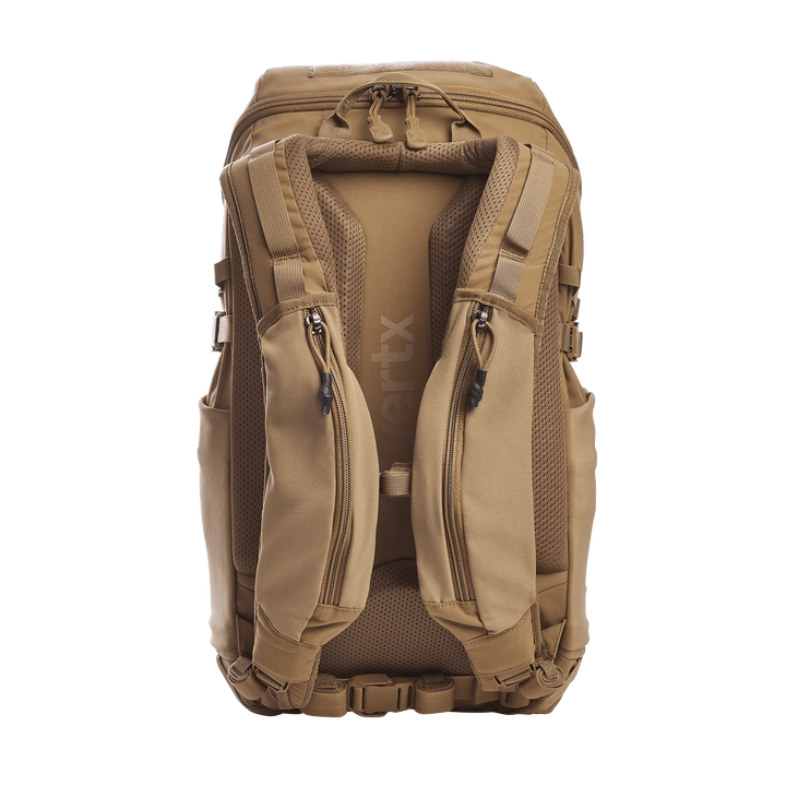The Vertx Siege 25L Tactical Pack, in brown, offers padded shoulder straps, multiple compartments, adjustable buckles, and a textured back panel for comfort. The Vertx brand is visible on the strap.