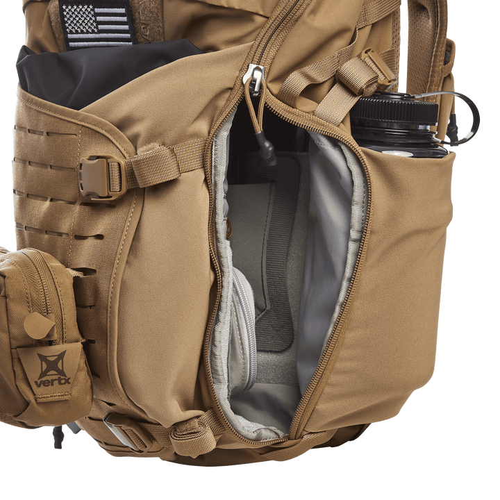 The tan Vertx Siege 25L Tactical Pack offers versatile features with a side pocket unveiling a gray pouch. It securely holds a black water bottle in an external holder, while MOLLE straps and a Velcro patch elevate its tactical functionality.