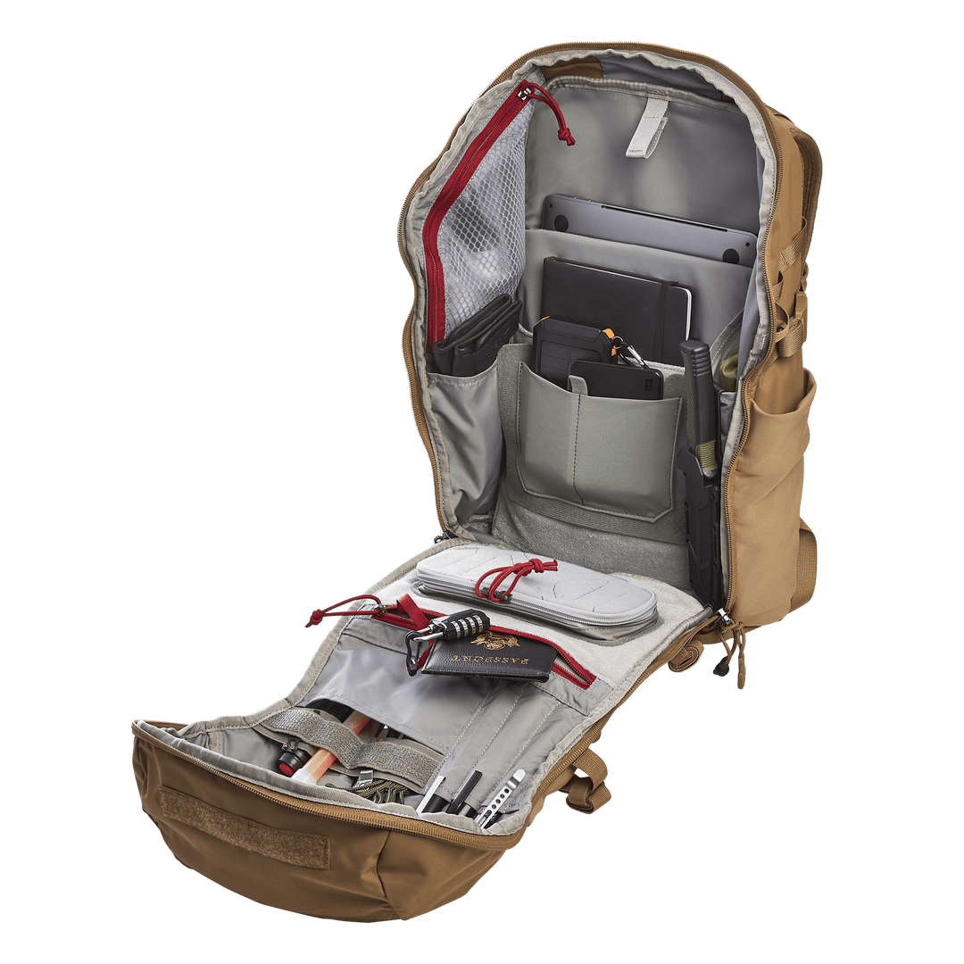 The Vertx Siege 25L Tactical Pack, in tan, opens fully to reveal organized compartments for tablets, cables, notebooks, pens, and essentials. Its tactical design includes mesh pockets and elastic bands for secure storage.