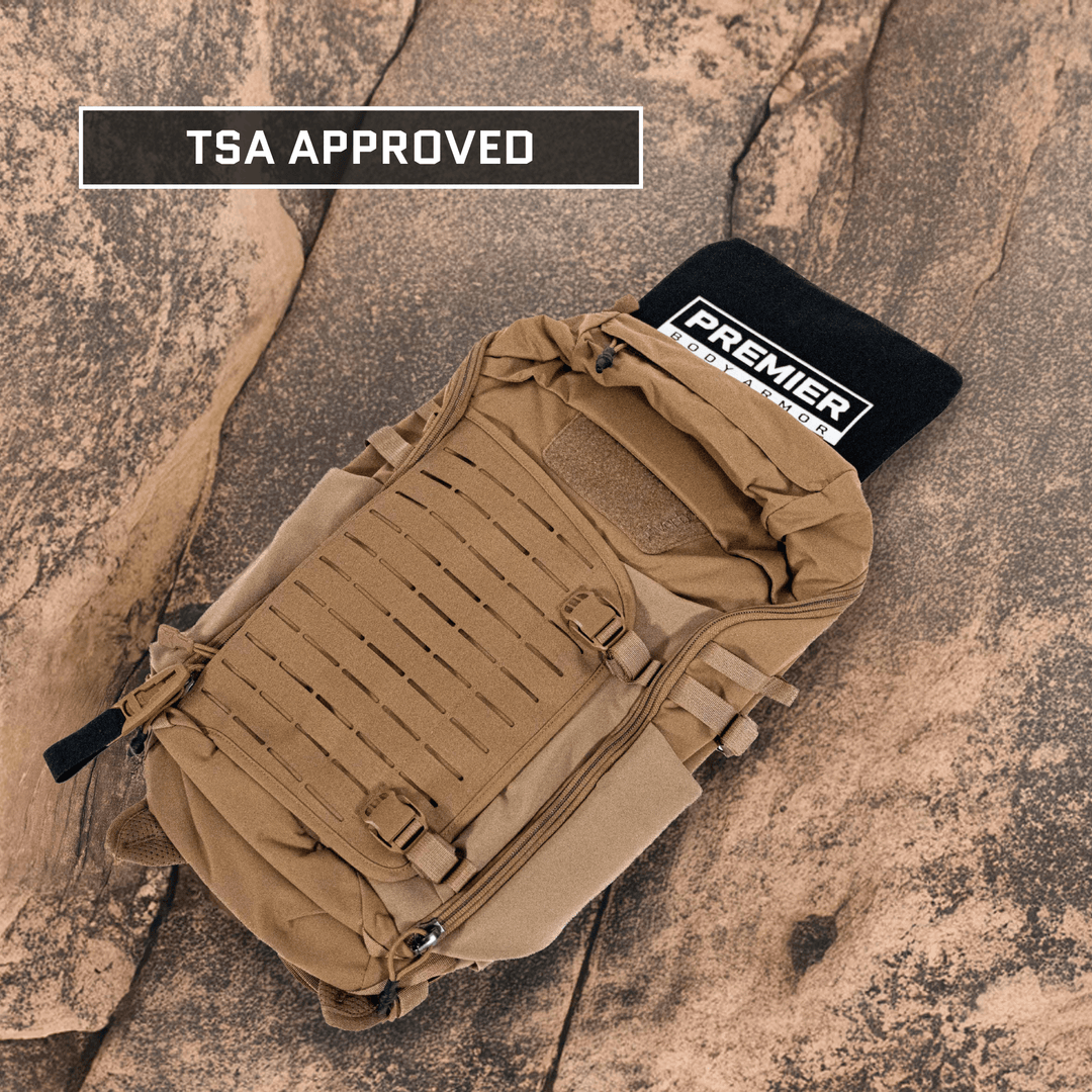 A tan tactical Vertx Siege Pack rests on a textured stone surface, featuring a black Premier Body Armor Level IIIA/HG2 insert visible at the top. A "TSA APPROVED" label decorates a box in the upper left.