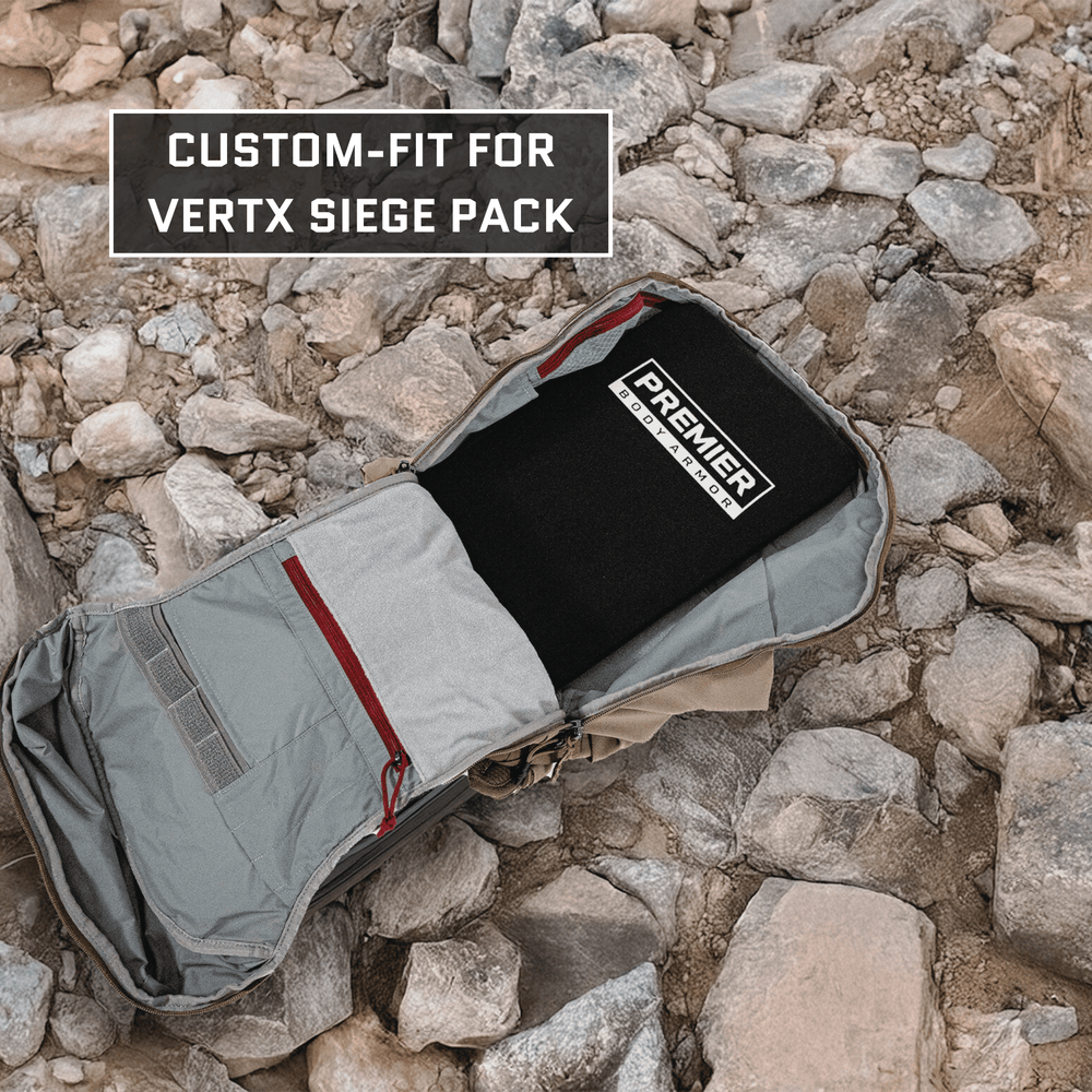 An open gray backpack with red accents lies on rocky ground, showcasing a Level IIIA ballistic insert labeled "Premier Body Armor." This custom-fit, Vertx Siege Pack backpack insert is emphasized by text in the top-left corner.
