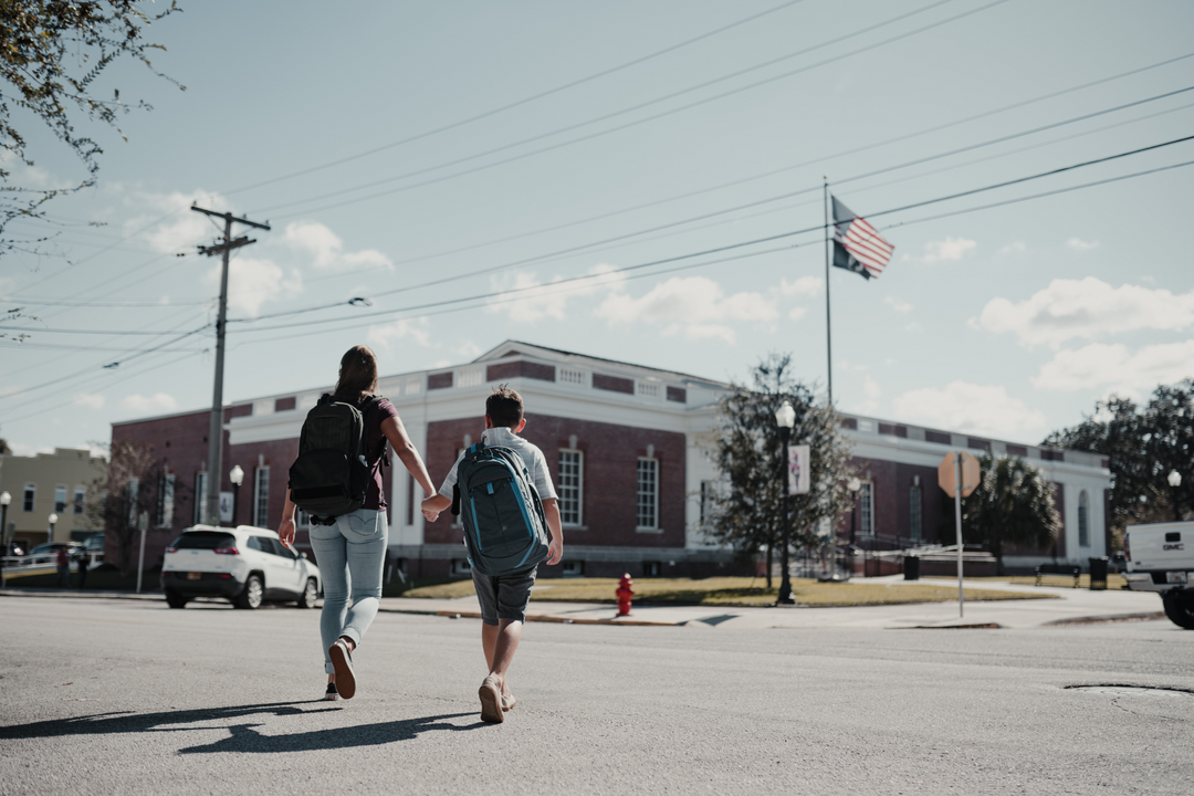 mom walking child to school wearing backpacks