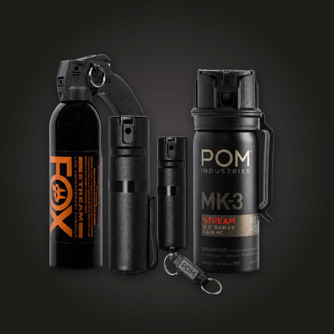 Four black canisters of pepper spray are displayed against a dark background. Two canisters are labeled, one with "FOX" in orange and one with "POM Industries MK3" in white.