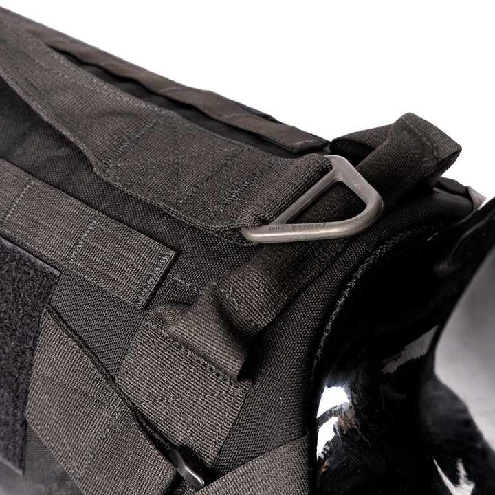 Close-up of the Premier Body Armor K-9 Vest – Level IIIA, showcasing a metal D-ring and Velcro straps. The material appears to be heavy-duty fabric, designed for durability and utility, with detailed stitching and reinforced areas.