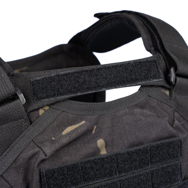 Close-up image showcasing the Core Mission Plate Carrier w/ Level IIIA Cummerbund Armor by Premier Body Armor in black, featuring various straps and Velcro patches. The material shows a few visible wear marks, highlighting its durability. Designed as a plate carrier for enhanced protection, the vest supports carrying additional equipment while maintaining sturdy construction.