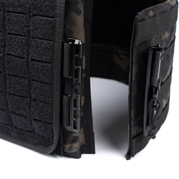 Close-up image of the Premier Body Armor Core Mission Plate Carrier with Level IIIA Cummerbund Armor featuring modular webbing and attachment points. The vest, part of a comprehensive tactical kit, has a black and dark camo pattern with clips and straps for securing additional gear. The material appears rugged and durable, suitable for outdoor or tactical use.