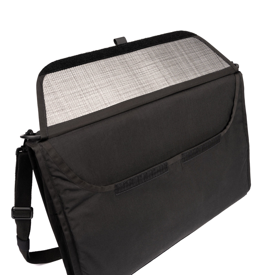 A Ballistic Briefcase from Premier Body Armor is displayed with its flap open, exposing an interior mesh lining. This sleek, minimalist black laptop bag includes an adjustable shoulder strap and is constructed from durable fabric, making it perfect for executive protection.