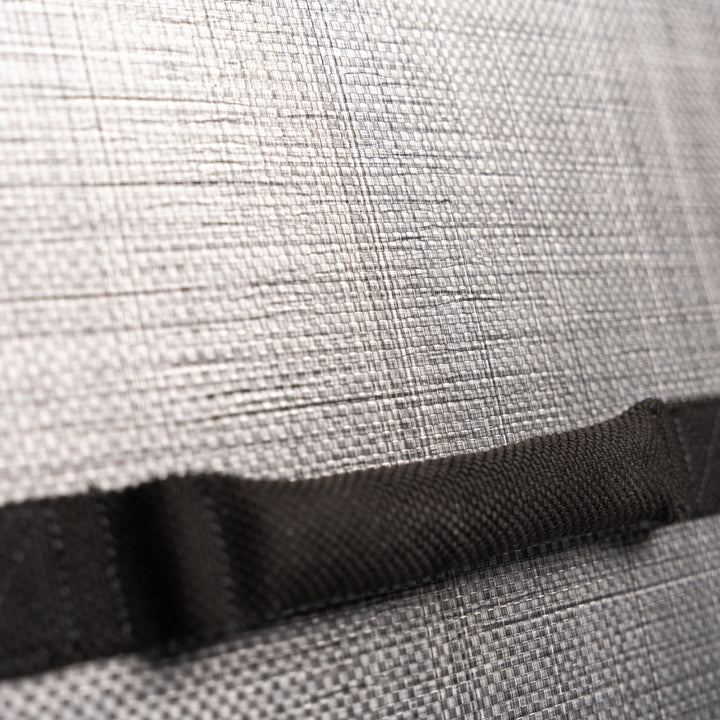 Close-up image of a textured, woven material in a light gray color. A black strap is horizontally attached across the fabric, with visible stitching. The strap's texture appears rough and sturdy. Reminiscent of Premier Body Armor's Ballistic Briefcase, the fabric has a pattern resembling thin intersecting lines.