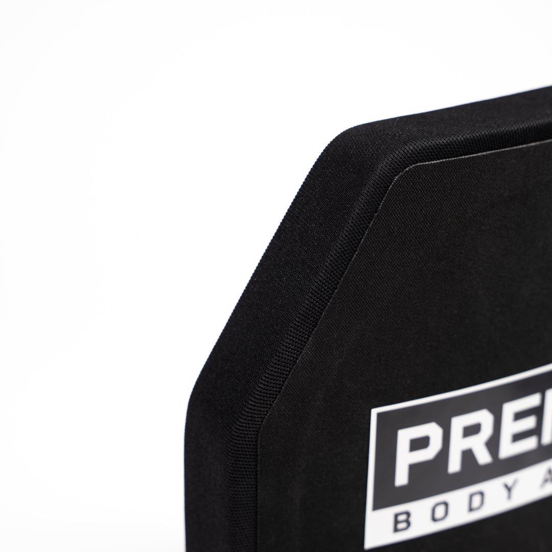 A close-up of the Premier Body Armor Fortis Patrol Level III+ black ballistic plate with a partially visible rectangular label on a white background highlights its lightweight ballistic protection.