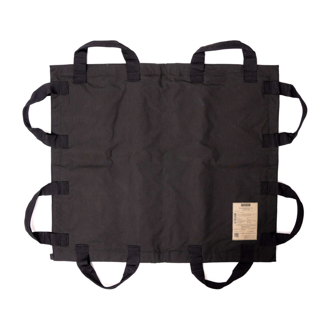 Introducing the Fortis Ballistic Blanket by Premier Body Armor: a robust, black transport bag crafted from high-quality Dyneema® fabric. Its symmetrical design includes multiple handles along the edges for easy carrying. A white label with printed information is positioned in one corner, and when laid flat, it displays its rectangular shape and sturdy construction typical of ballistic blankets.