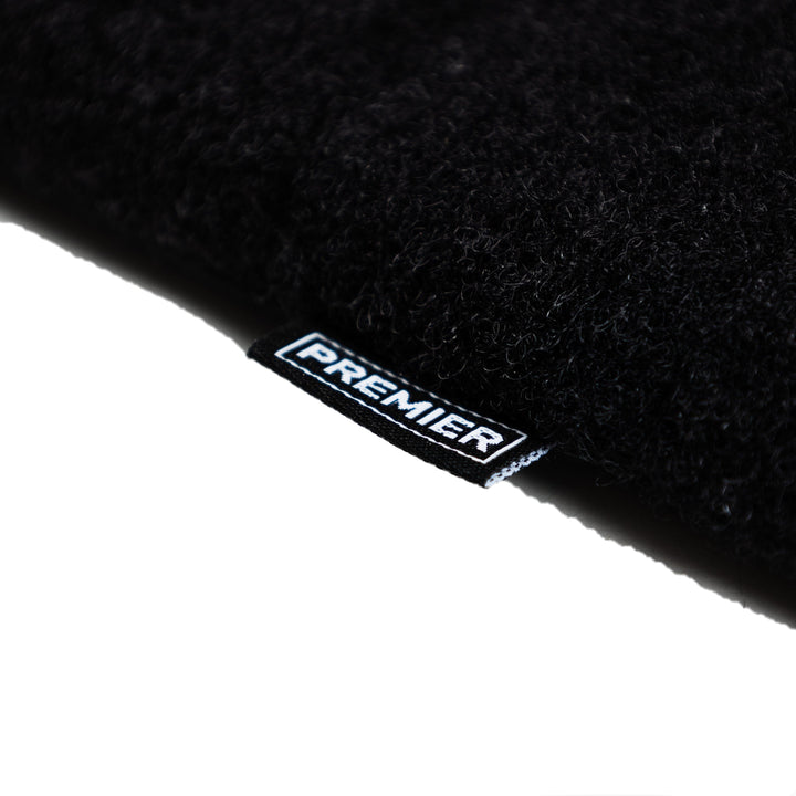 A close-up image of a black fabric item, likely part of the Fieldcraft Survival Small Mobility Level IIIA Bag Insert by Premier Body Armor, shows a small woven label with the word "PREMIER" in white text sewn onto the edge. The fabric has a textured appearance. The background is plain and white.