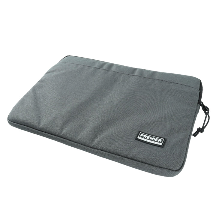 A gray fabric Bulletproof Laptop Case from Premier Body Armor features a horizontal zipper at the top and a small black rectangular label reading "PREMIER" on the lower right corner. The case offers Level IIIA protection and has a minimalistic design, making it perfect for secure travel while being TSA approved.