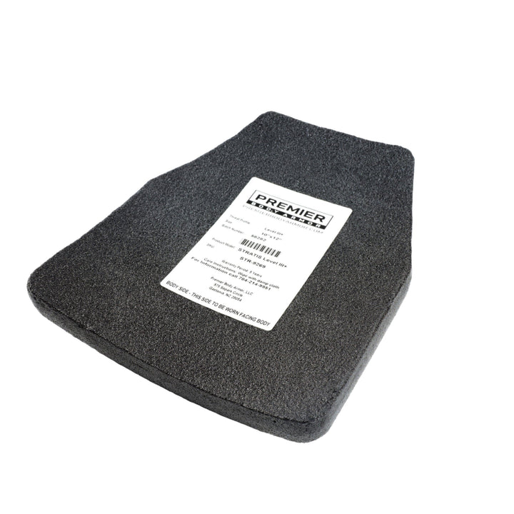 A dark gray rectangular Premier Car Mat with a slightly trapezoidal shape. The mat features a label with text that includes the brand name, "Premier Body Armor," and other product details. The textured material adds an element of personal protection, akin to STRATIS Level III+ MC body armor plates.