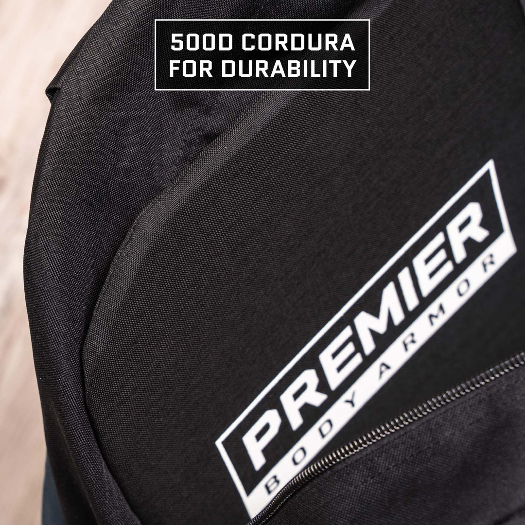 Close-up of a black backpack featuring two labels: a small one with the text "500D Cordura for Durability" and a larger one reading "Premier Body Armor." The material appears sturdy and well-constructed, similar to the robust Eberlestock Fade Brief Level IIIA Insert.