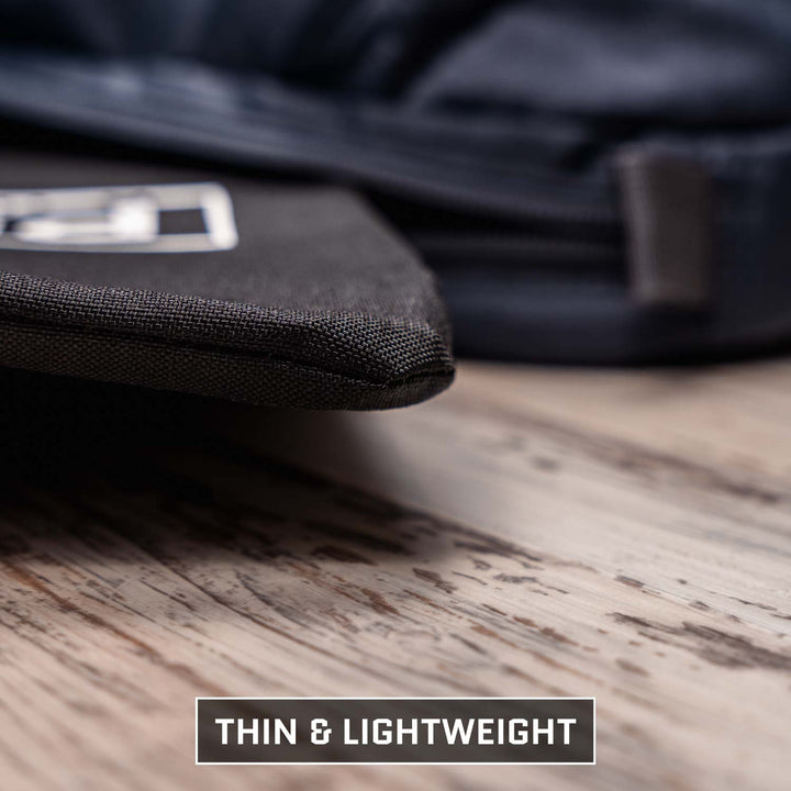 Close-up of a thin edge black fabric case on wood, with another barely visible in the back, resembling the Viktos/Premier Armored Viktos Upscale Hip Pack Bundle. Text reads "THIN & LIGHTWEIGHT.