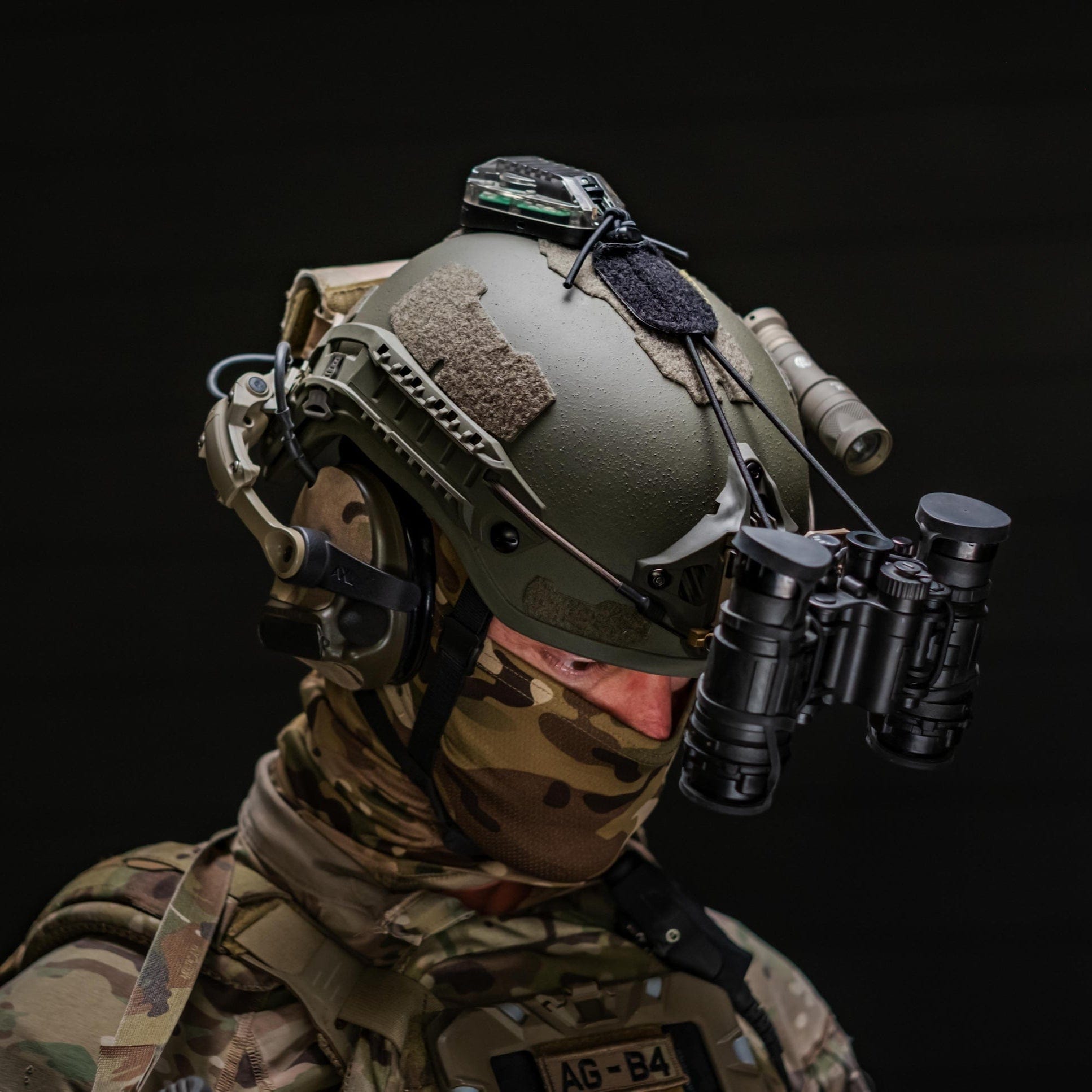 Person wearing a fortis ballistic level 3a helmet with electronic equipment on a black background