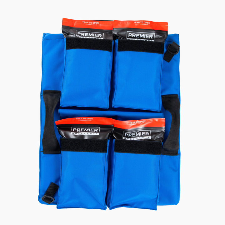 Image of a blue First Aid Shield medical supply pack with black handle straps. It has four sealed pouches labeled "Premier Body Armor" in black and orange. Each pouch has "Tear to Open" written at the top. This emergency response kit appears to be designed for easy transport and access, promoting school safety.