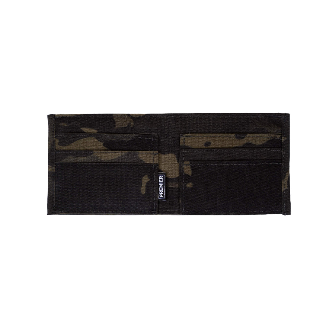 A Premier Body Armor Bulletproof Wallet in black and dark camouflage is shown. The wallet is opened to display its interior, which includes multiple pockets for storing items. A visible fabric label that reads "Made in the USA" is sewn into the center area of one of the sections.