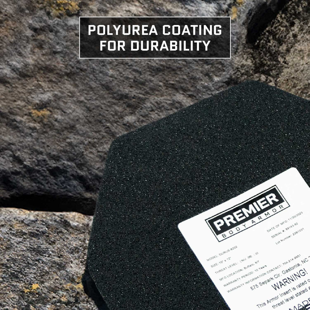 A black armor plate known as the "Durus 650 Level III+ Plate" by Premier Body Armor rests on rocks, showcasing its durable polyurea coating. With a textured surface and multi-curve design, it emphasizes advanced ballistic protection.