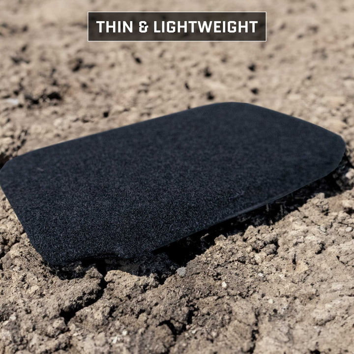 A black, thin Eberlestock Bando Bag XL Level IIIA Insert on dry, cracked soil. Text above reads "Thin & Lightweight," hinting at the advanced properties of the Premier Body Armor ballistic material.