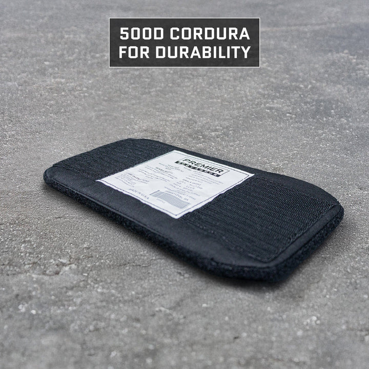 A black rectangular padded item with a white label lies on a gray concrete floor. Above it, text reads "500D CORDURA FOR DURABILITY," highlighting the rugged reliability of Premier Body Armor's Eberlestock Fade Flex Level IIIA Insert ballistic package.