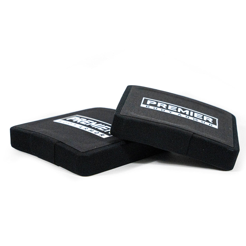 Two black rectangular foam pads, identified as the "Fortis III+/RF1 Side Plate Set," are placed against each other on a white surface. With slightly curved edges, these pads prominently display the "Premier Body Armor" logo in white, ensuring reliable protection and peace of mind.