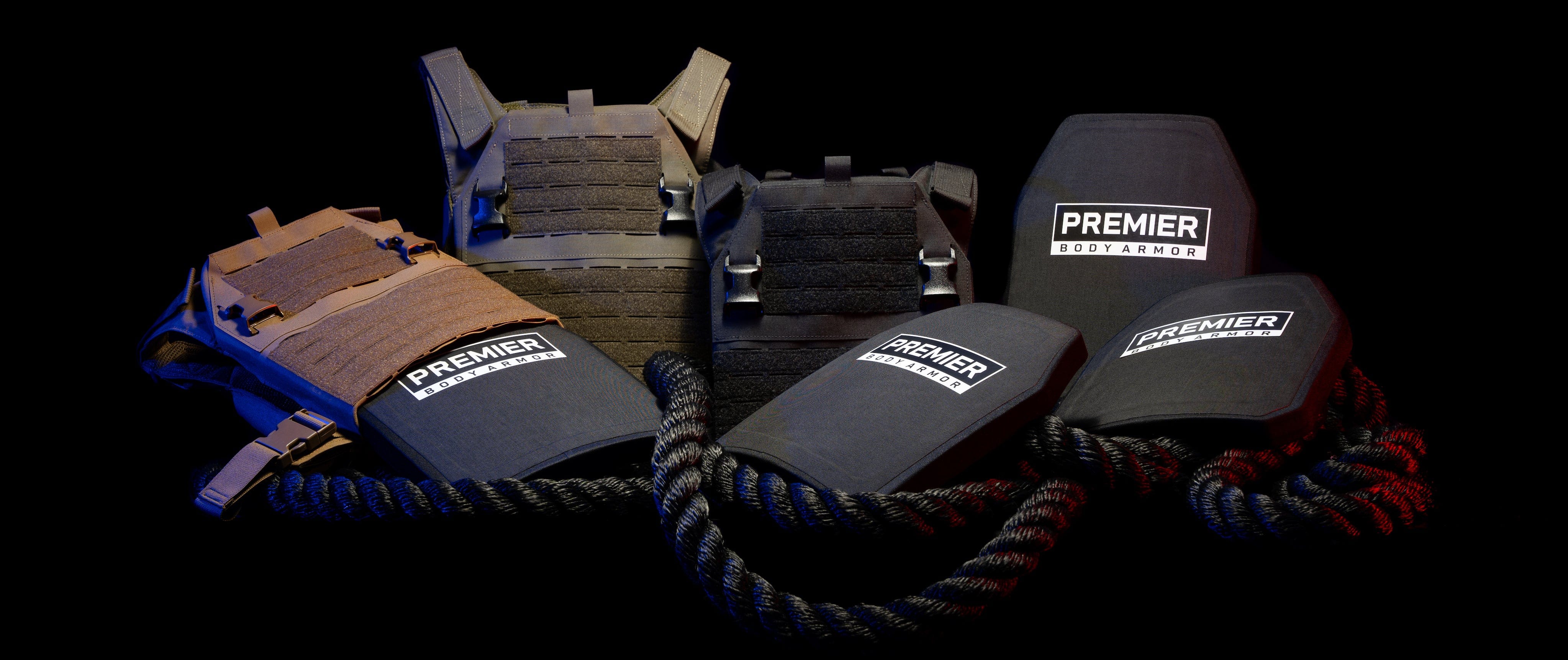 The image shows five pieces of body armor with "Premier Body Armor" labels. The armors are displayed against a dark background, surrounded by thick ropes. The armors vary in design and include both vests and plate carriers.