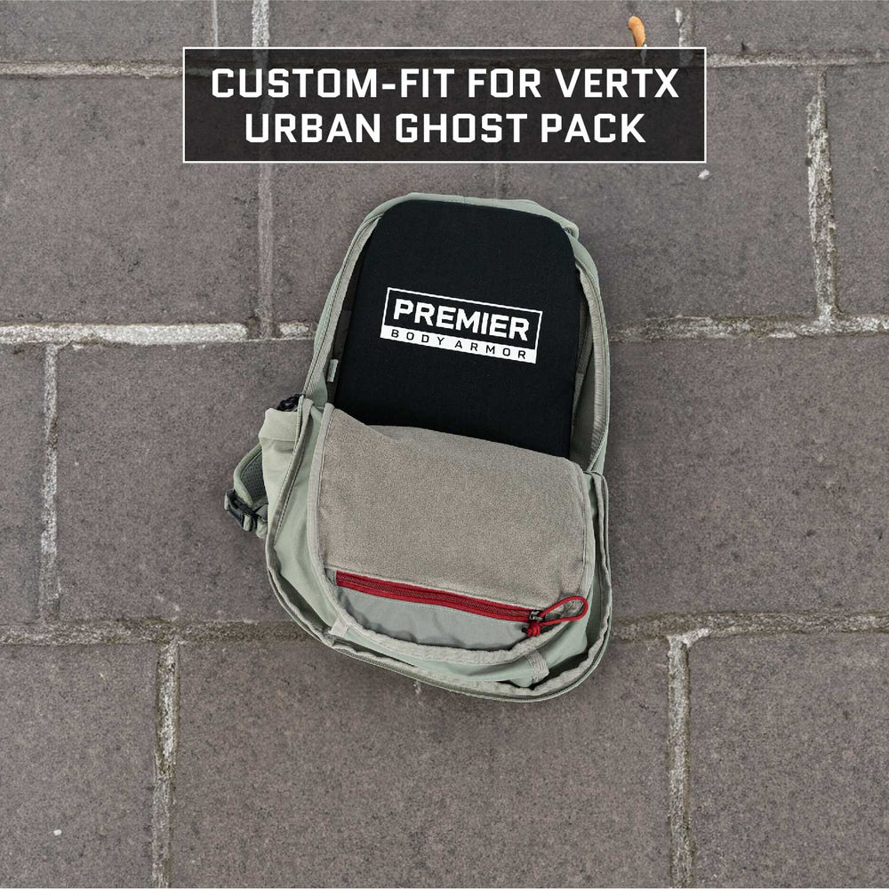 A grey Armored Vertx Ghost Pack Bundle featuring a red zipper is open, unveiling a black item inscribed with "Premier Body Armor." Above the scene, the text reads, "Custom-fit for Armored Vertx Ghost Pack." Designed for tactical professionals in need of ballistic protection, the backpack is displayed on stone pavement.