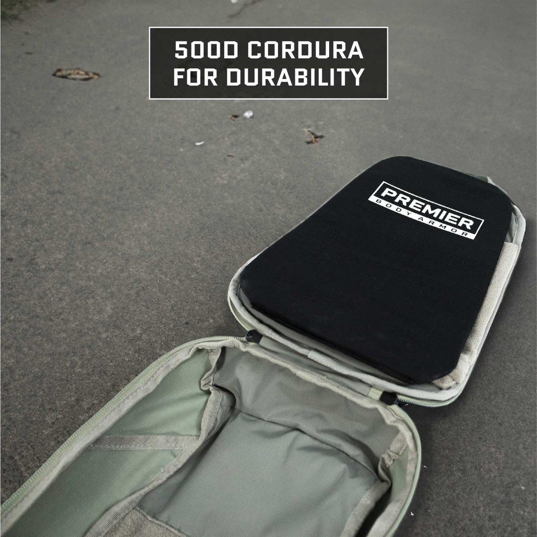 A grey backpack lies open on a concrete surface, showcasing a black, rectangular insert from Premier Body Armor labeled "Vertx Ghost Sling Level IIIA/HG2 Backpack Insert." The text "500D Cordura for durability" is featured above it. The interior is visible and specially designed to accommodate the Vertx Ghost Sling or a ballistic panel.