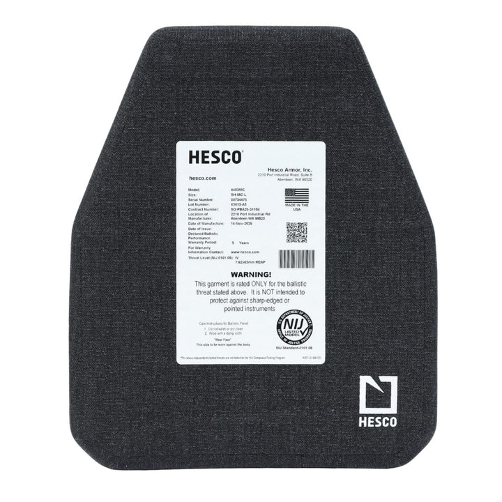 A Hesco 4403MC Level IV Plate ballistic armor plate features a visible product label with specs, warnings, and certification info on a white background. The lightweight dark gray ceramic plate has angled corners.