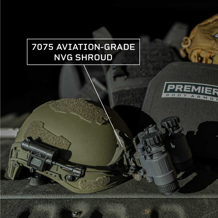 A close-up of the Fortis Ballistic Helmet by Premier Body Armor highlights a ballistic helmet with night vision goggles and a 7075 aviation-grade NVG shroud, alongside lightweight body armor, all illuminated under focused light.