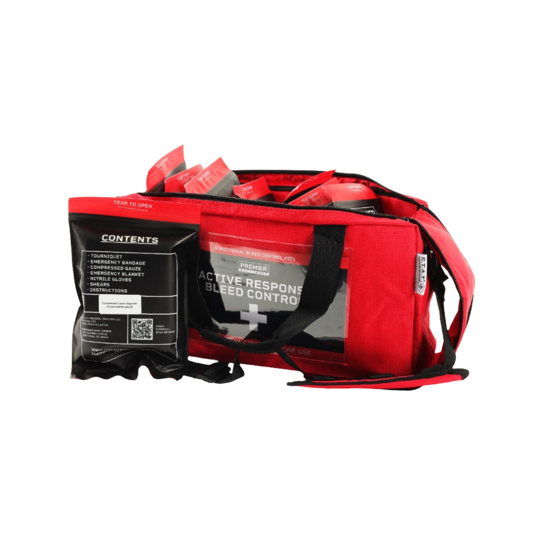 The Active Response Bleed Control Kit by STAT consists of a red emergency response bag filled with medical supplies, such as bandages, gloves, and medication packets. Accompanied by a smaller black pouch labeled with its contents, the main bag also includes essential items like the bleed control kit and S.T.A.T. Tourniquet. Designed with multiple compartments and secured by a zipper closure, this kit offers comprehensive preparedness for emergencies.