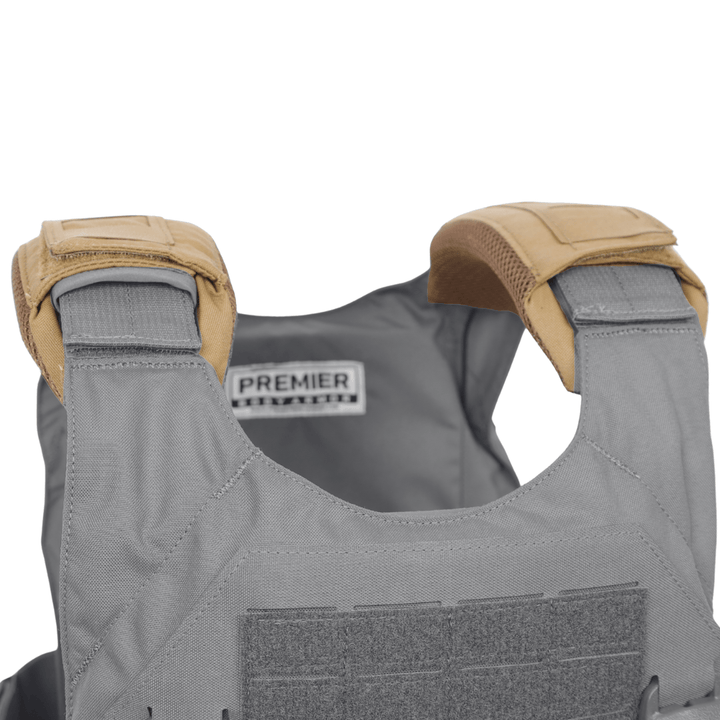 A close-up of the upper section of a gray tactical vest showcases tan Fortis Shoulder Pads from Premier Body Armor. A fabric label with “PREMIER” branding is visible inside the back of the vest. Premier Body Armor offers military and law enforcement discounts on select gear, making it easier for those who serve to access high-quality protection.
