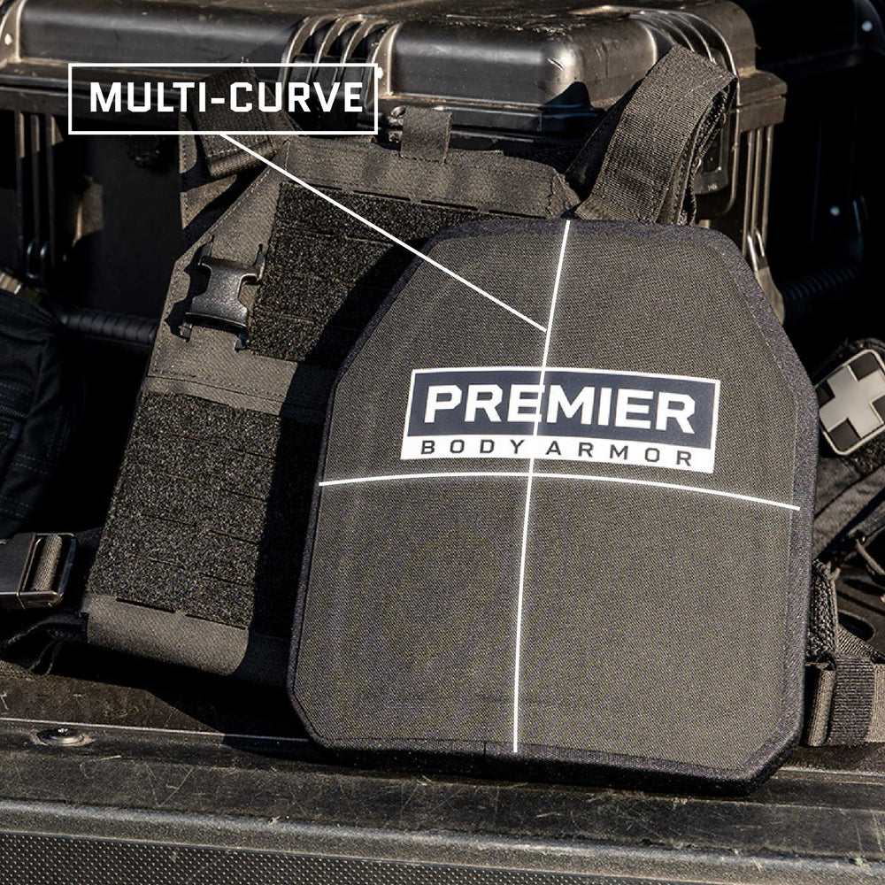 Close-up of a piece of Premier Body Armor's Fortis III+ GT/RF2 Multi-Curve design lying on equipment. There is a label indicating it has a multi-curve design. The black body armor features a white cross pattern and the "PREMIER BODY ARMOR" logo prominently centered, ensuring optimal ballistic protection.