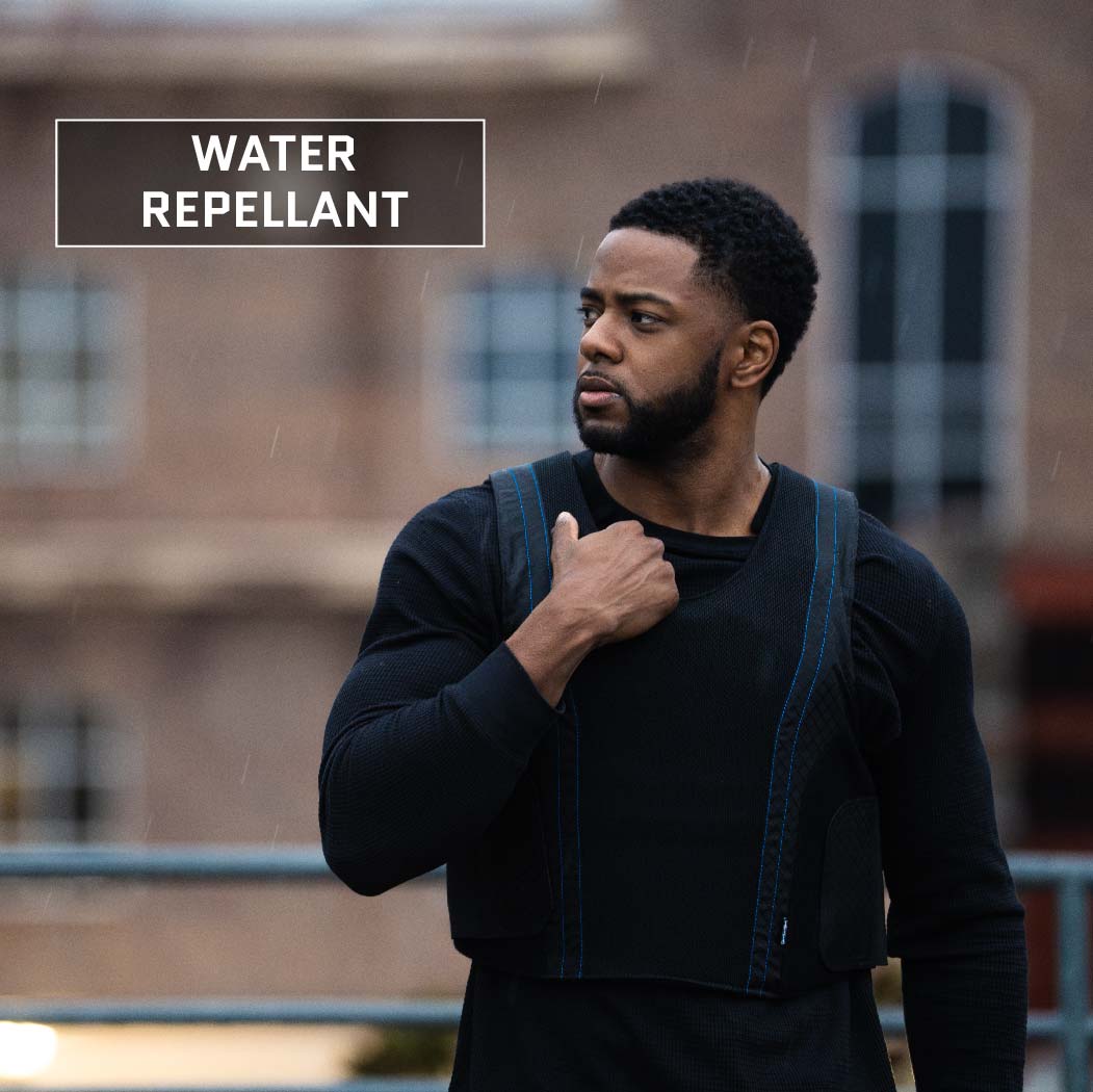 A person stands outdoors wearing a black, long-sleeve athletic shirt with a Premier Body Armor Concealable Armor Vest - Level IIIA over it. The word "Water Repellant" is displayed in the top left corner of the image, suggesting that the Made in the USA vest is designed to repel water.