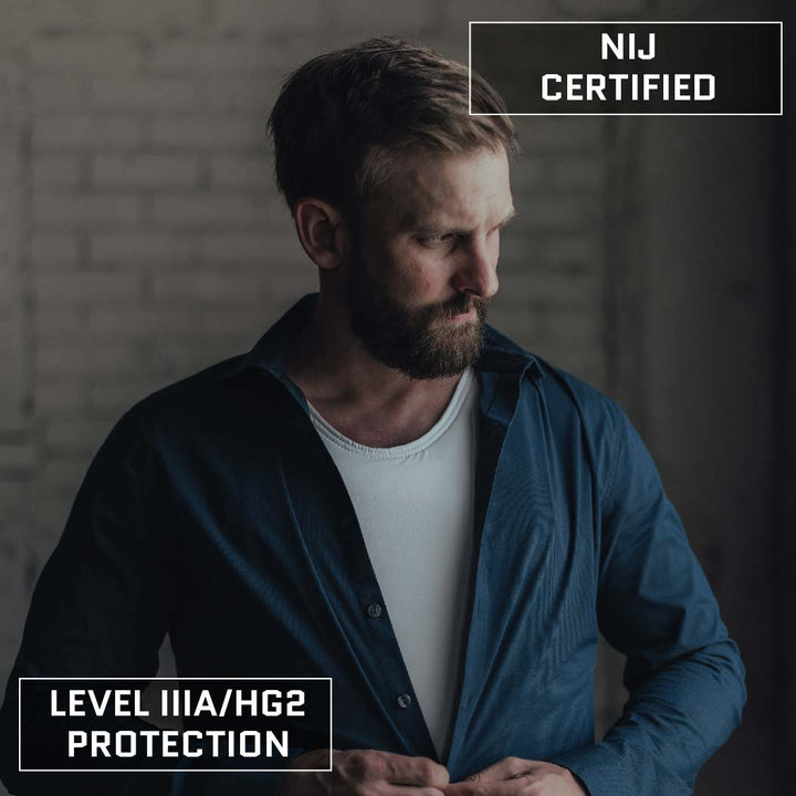 A bearded man adjusts his blue button-up shirt, open to reveal a white undershirt concealing a Premier Body Armor Discreet Executive Vest - Level IIIA. Text overlays on the image state "NIJ Certified Level IIIA" and "Level IIIA/HG2 Protection," while the out-of-focus background emphasizes the man in the foreground.