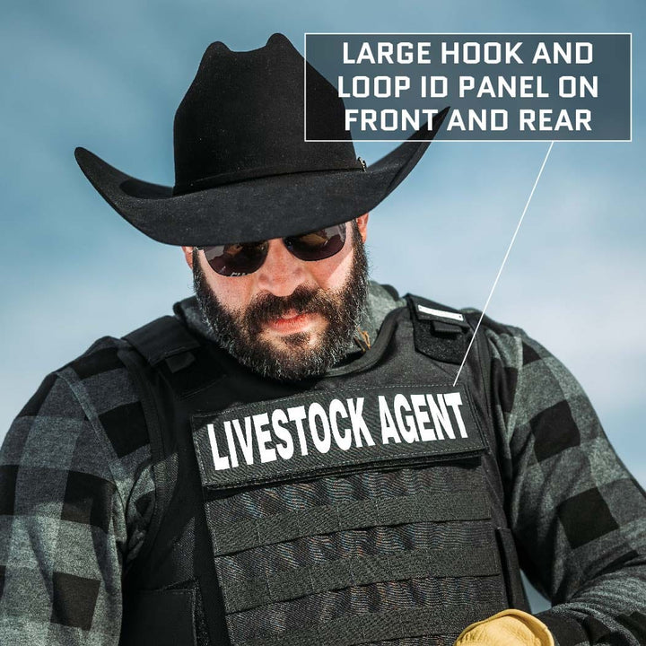 A person wearing a black cowboy hat, dark sunglasses, and a plaid shirt is shown facing forward. They are wearing an "Overt / Covert Vest Bundle (old)" by Premier Body Armor labeled "LIVESTOCK AGENT." An annotation points to the vest, highlighting a "LARGE HOOK AND LOOP ID PANEL ON FRONT AND REAR.