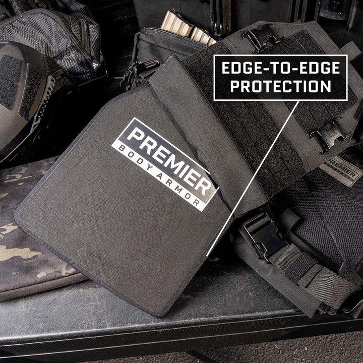 A Premier Body Armor plate is displayed with the label "EDGE-TO-EDGE PROTECTION." The black Fortis IV/RF3 ballistic plate, featuring the Premier Body Armor name and logo, is part of a tactical gear setup that includes additional armor pieces, UHWMPE Aluminum Oxide for multi-hit protection, and ammunition.