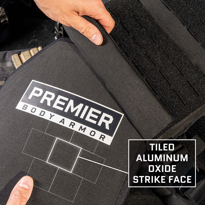 A person adjusts a piece of black body armor labeled "Premier Body Armor." Next to it, a label reads, "Tiled Aluminum Oxide Strike Face." The image shows close-up details of the UHWMPE Aluminum Oxide construction and multi-hit protection offered by this Level IV Fortis IV/RF3 ballistic plate.