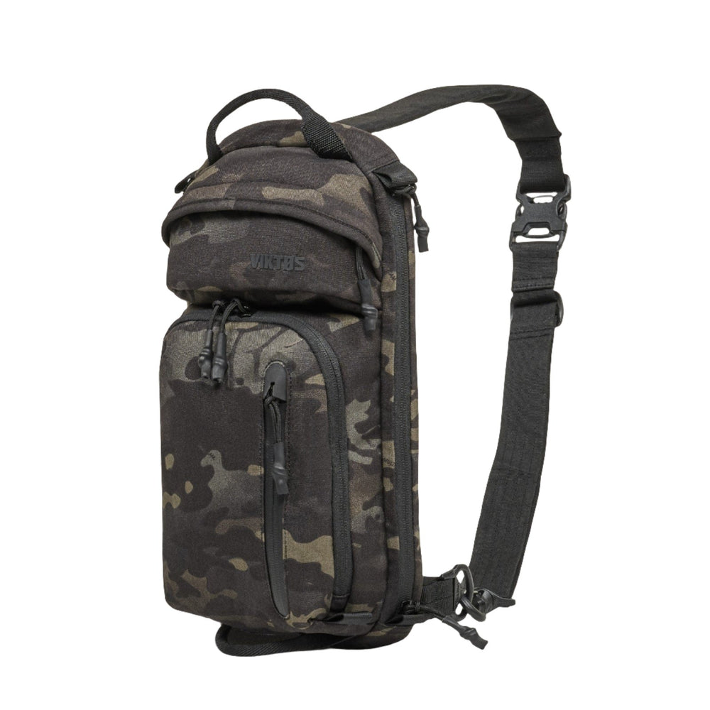 The Viktos Upscale 3 Sling in black camouflage is a versatile CCW sling bag with multiple compartments and zippers. It features a branded label on the front lower compartment, a wide adjustable shoulder strap with an easy-wear clip, and space for a concealed carry body armor insert. Additionally, it has a top handle for alternative carrying options.