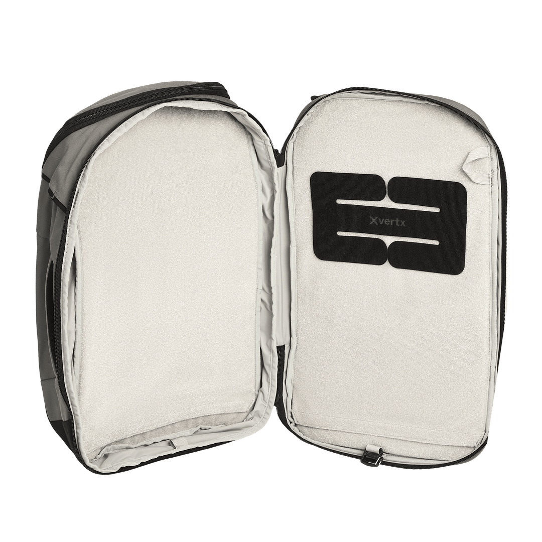 A Vertx Gamut 22L Sling backpack by Vertx is fully unzipped, revealing a spacious, light-colored interior with a black "Vertx" patch. The travel-friendly design includes a dedicated CCW compartment. No items are inside the backpack.